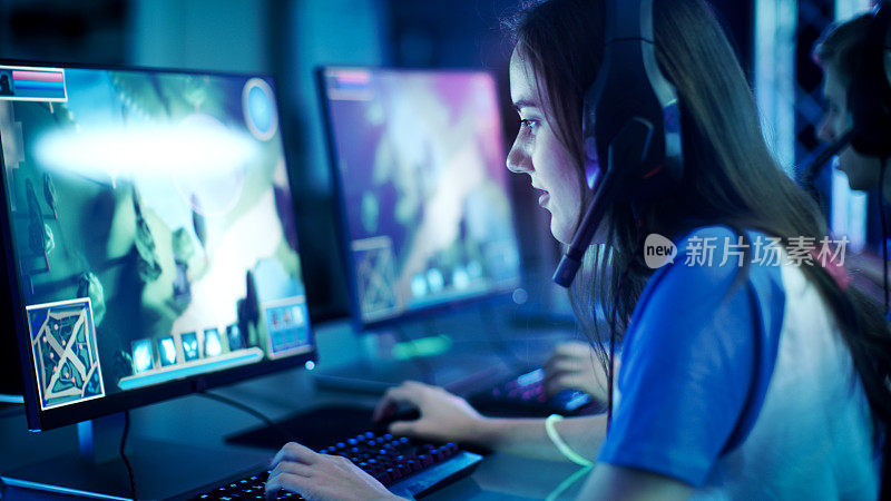 职业女性玩家在她的电脑上玩MMORPG/策略电子游戏。她参加网络游戏比赛，在家里玩，或在网吧玩。她戴着游戏耳机。
